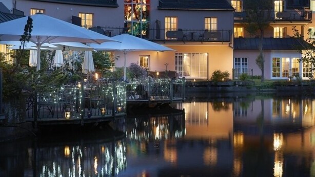 A waterfront hotel with outdoor seating and a reflection pool. - Hotel Molitors Mühle (Eisenschmitt)