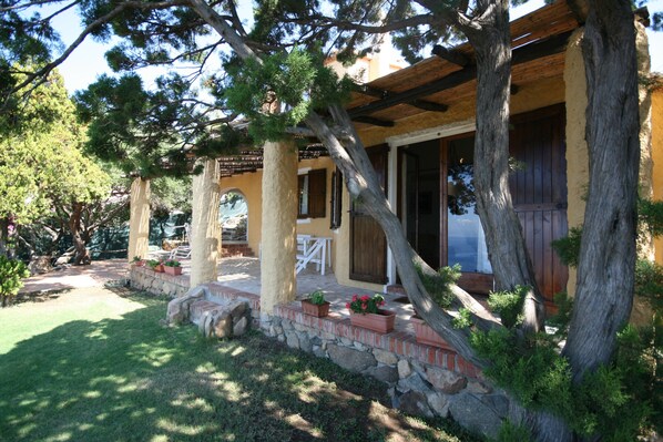 A covered outdoor patio with stone steps, wooden columns, and potted plants.
