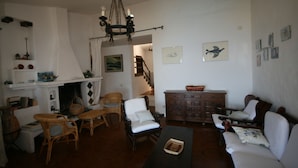 A living room with wicker furniture, a fireplace, a chandelier, and a staircase leading to another room. - Villa Gianina (Maracalagonis)
