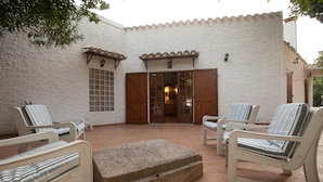 Un patio con mobiliario blanco y un banco de piedra.