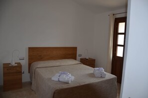 A bedroom with a wooden headboard, a single bed, two bedside tables, and a door with a window.