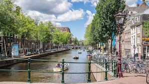 A canal with boats, lined with trees and historic buildings. - Hotel Frank since 1666 (Amsterdam)