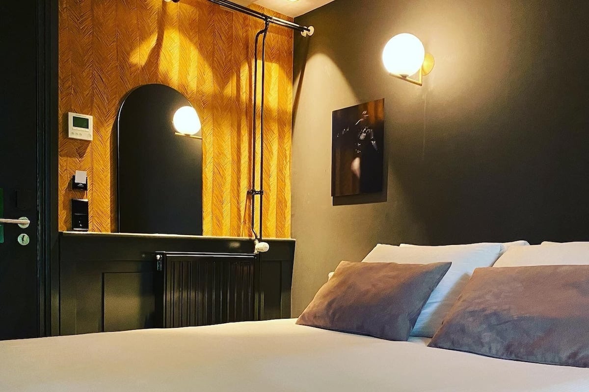 A hotel room with a large bed, a wooden headboard, a wall-mounted mirror, and a picture frame.