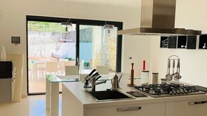 A modern kitchen with a central island, stainless steel appliances, and a view to an outdoor patio.