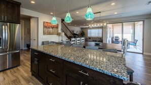 A spacious kitchen with a large granite island, stainless steel appliances, and pendant lighting. - Vermillion Oasis: Luxury 6BR/7BA Home near Zion. Private Pool & Resort Amenities (Santa Clara)