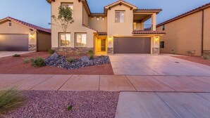 A two-story house with a garage, a landscaped front yard, and a driveway. - Vermillion Oasis: Luxury 6BR/7BA Home near Zion. Private Pool & Resort Amenities (Santa Clara)