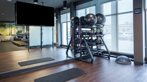 A gym with exercise equipment, a television, and large windows. - Courtyard by Marriott Kansas City Olathe (Olathe)