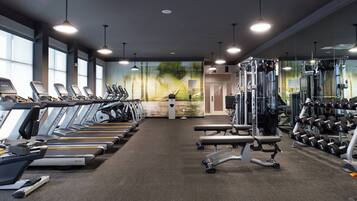 Un gimnasio con cintas de correr, máquinas de pesas y mancuernas.