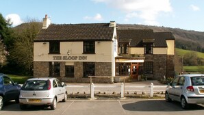 The Loop Inn, a two-story building with a stone facade and tiled roof, featuring a parking lot with several cars.