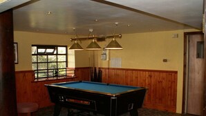 A pool table in a room with wooden paneling, a window, and a door.