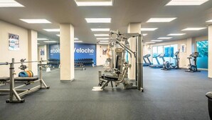A gym with weightlifting equipment, treadmills, and a blue wall with 'VeloChe' branding. - The Ark By Veloche Group (Karon)