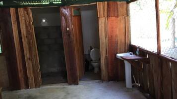 A rustic bathroom with wooden walls, a toilet, and a sink with a soap dispenser.
