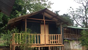 A wooden cabin with a balcony and a door, surrounded by trees.