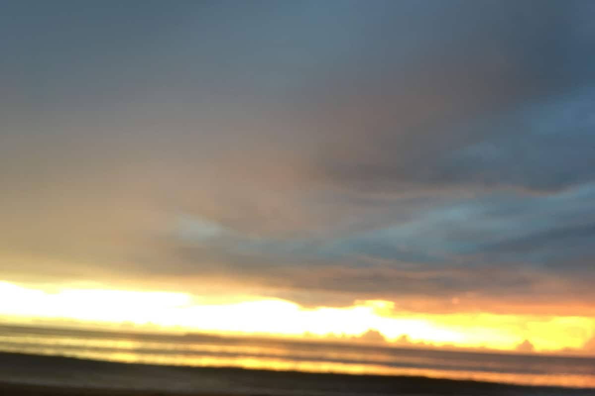 Atardecer sobre una masa de agua con cielo despejado.