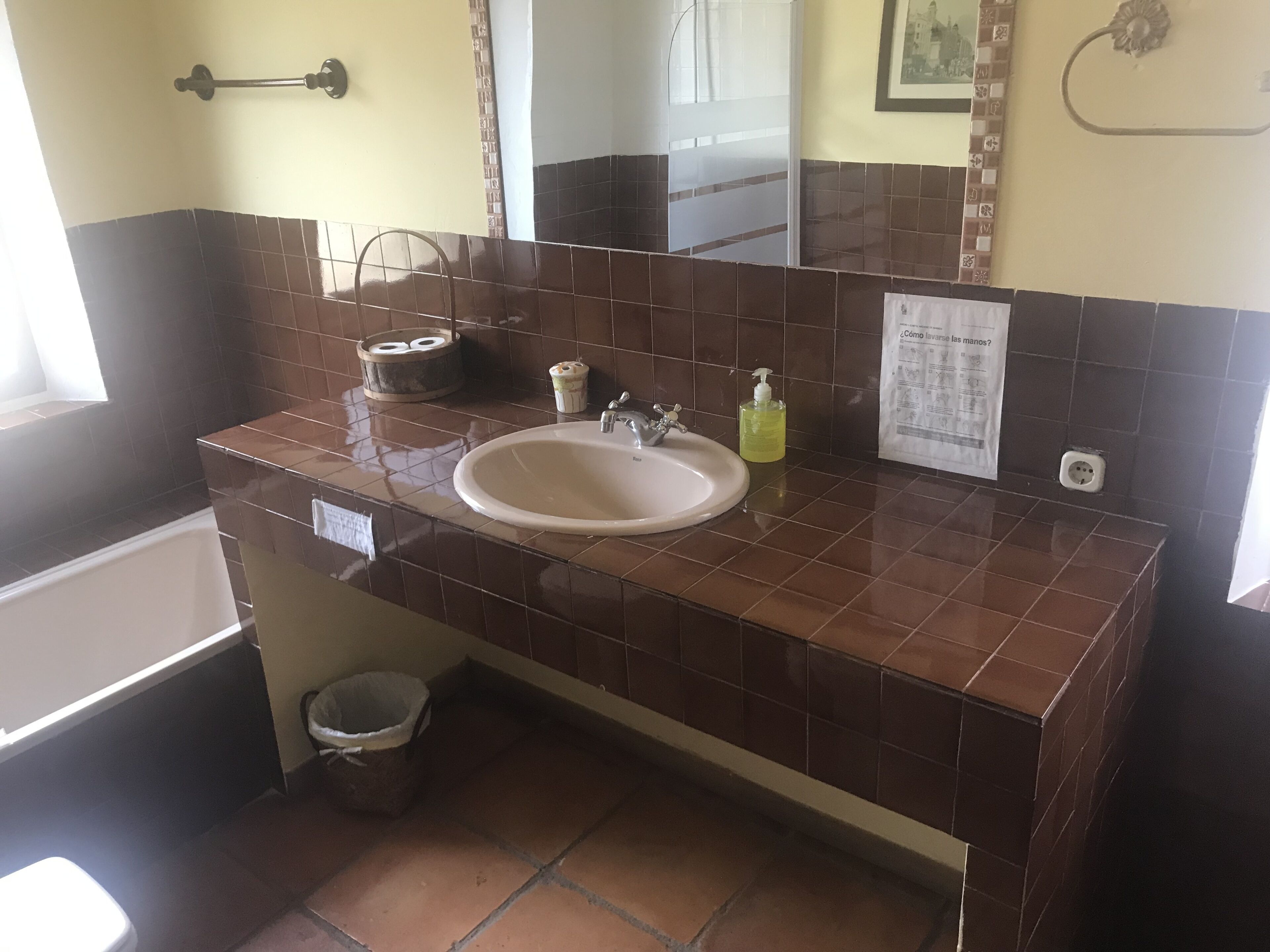 Een badkamer met een wastafel, spiegel en betegelde wanden.