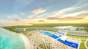 Un complexe hôtelier doté de plusieurs piscines, d’une plage et d’un grand bâtiment surmonté d’un toit végétalisé.