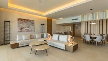 Amplia sala de estar con sofá modular, mesa de centro redonda y comedor con mesa y sillas.