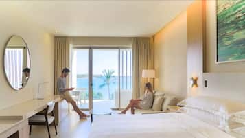 Una habitación de hotel con cama, escritorio, silla, un ventanal con vistas y un cuadro en la pared.