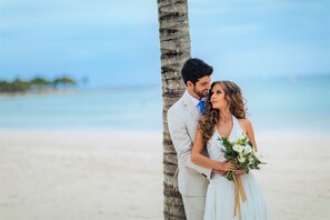A couple on a beach with a palm tree and ocean in the background. - Barcelo Maya Riviera (Xpu-Ha)