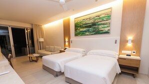 A hotel room with two beds, a sofa, a desk, and a sliding glass door leading to a balcony. - Barcelo Maya Riviera (Xpu-Ha)