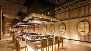 Un restaurant moderne doté d’un îlot central, de chaises en bois et d’un décor mural original avec des motifs circulaires.