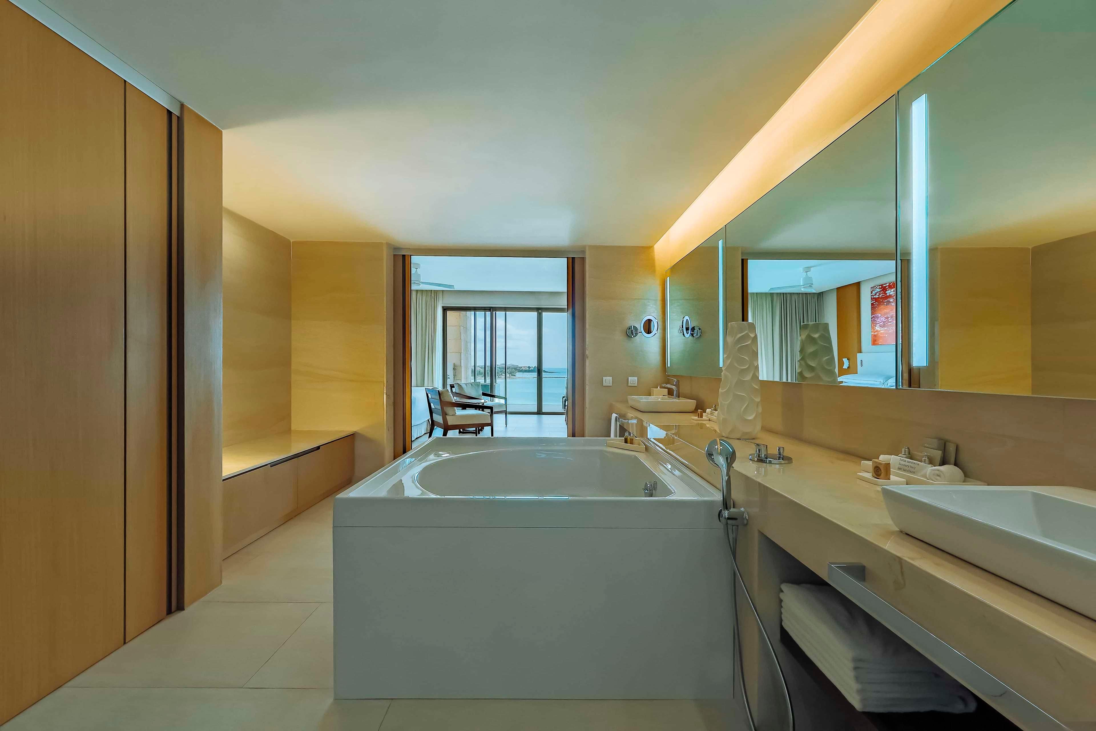 Un baño moderno con una bañera grande, dos lavamanos y un espejo amplio.