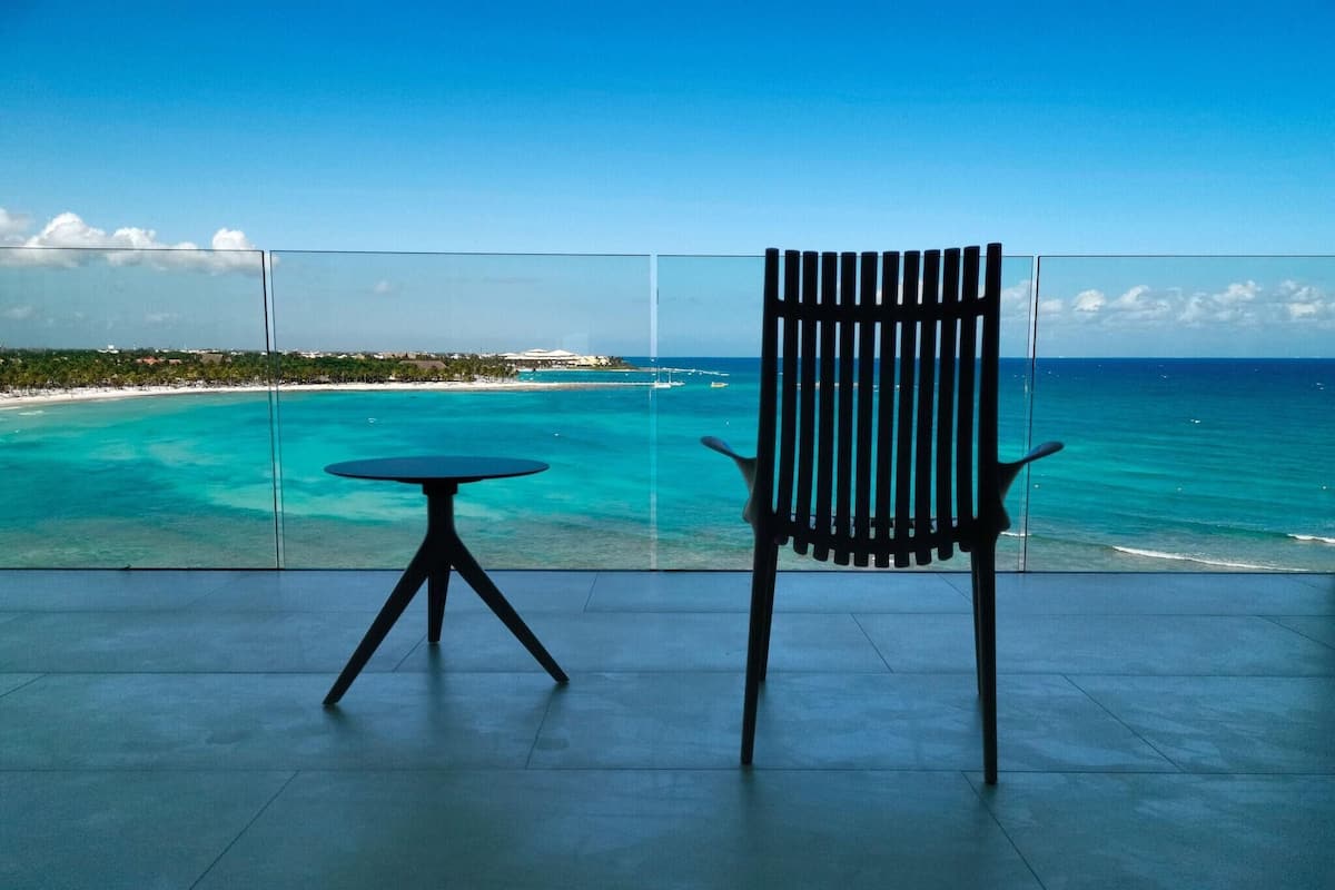 A balcony with a view of turquoise waters and a distant shoreline.
