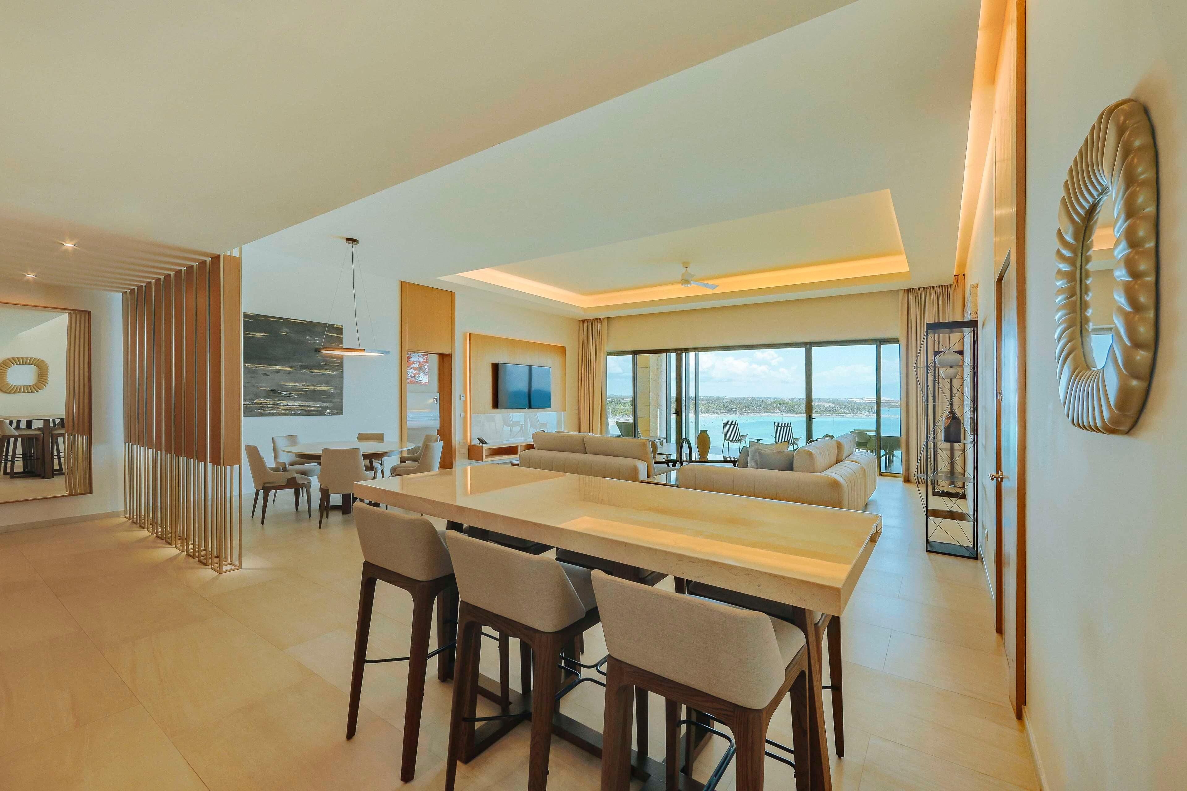 A spacious living area with a large dining table, comfortable seating, and a view of the ocean.