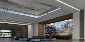 A spacious lobby with a high ceiling, a large abstract mural, and a seating area with a view of palm trees. - Barcelo Maya Riviera (Xpu-Ha)