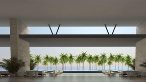 Un espace intérieur vaste et lumineux, avec vue sur les palmiers et l’océan.