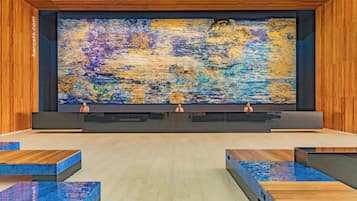Un área de recepción con un cuadro abstracto de gran tamaño, paneles de madera y un mostrador moderno.