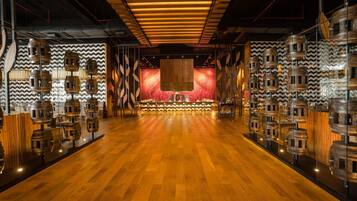Una habitación amplia con suelo de madera, un escenario central y decoraciones con barriles de madera en las paredes.