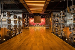 A spacious room with a wooden floor, a central stage, and wooden barrel decorations on the walls. - Barcelo Maya Riviera (Xpu-Ha)