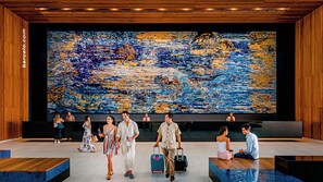 A modern lobby with a large abstract painting, wooden paneling, and a seating area. - Barcelo Maya Riviera (Xpu-Ha)