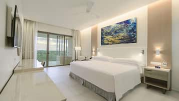 Habitación de hotel con una cama grande, un escritorio, una silla, un televisor, un cuadro y un balcón con vistas.