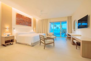 A hotel room with a bed, a desk, a chair, a TV, and a balcony with a view. - Barcelo Maya Riviera (Xpu-Ha)