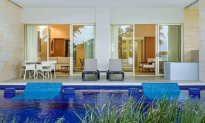 Un área de piscina moderna al aire libre con barandilla de vidrio, dos sillones de descanso y una mesa de comedor con sillas.