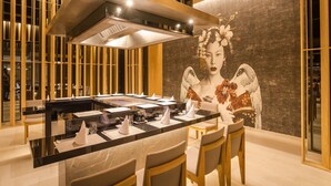 A modern dining area with a central island, wooden paneling, and a mural of a traditional figure.