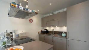 A modern kitchen with a central island, stainless steel appliances, and a microwave. - Stylish 1 Bedroom Apartment near London City (London)
