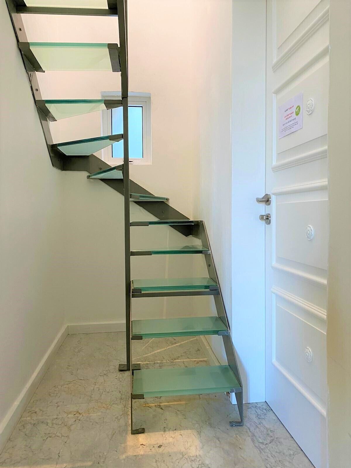 A spiral staircase with glass steps leading to a landing.
