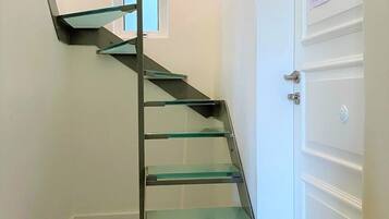 A spiral staircase with glass steps leading to a landing.
