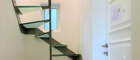 A spiral staircase with glass steps leading to a landing.