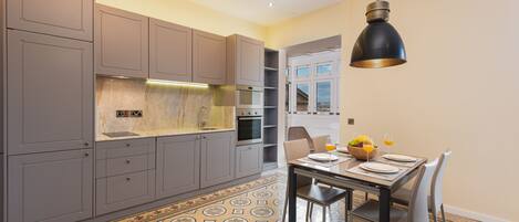 A modern kitchen with grey cabinets, a central island, and a dining area with a table set for two.