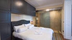Een hotelkamer met een groot bed, een donkere houten garderobe en een muurschildering.
