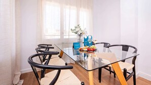 A modern dining area with a glass table, black chairs, and a blue menu stand.