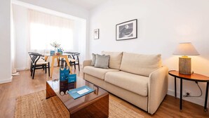 A living room with a sofa, coffee table, and a dining area with chairs and a table.