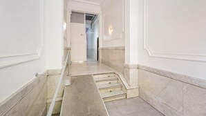 A corridor with marble flooring and white walls, leading to a staircase. - Sweett | Rocafort 604 (Barcelona)