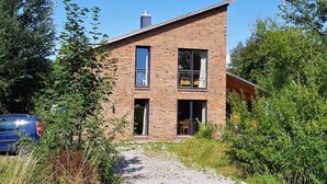 A modern two-story brick house with large windows, a visible balcony, and a gravel driveway. - Vacation home at Süderdeich in Friedrichskoog (Friedrichskoog)