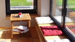 A small room with a window, a wooden bench, a small table, and a bed with pillows. - Vacation home at Süderdeich in Friedrichskoog (Friedrichskoog)