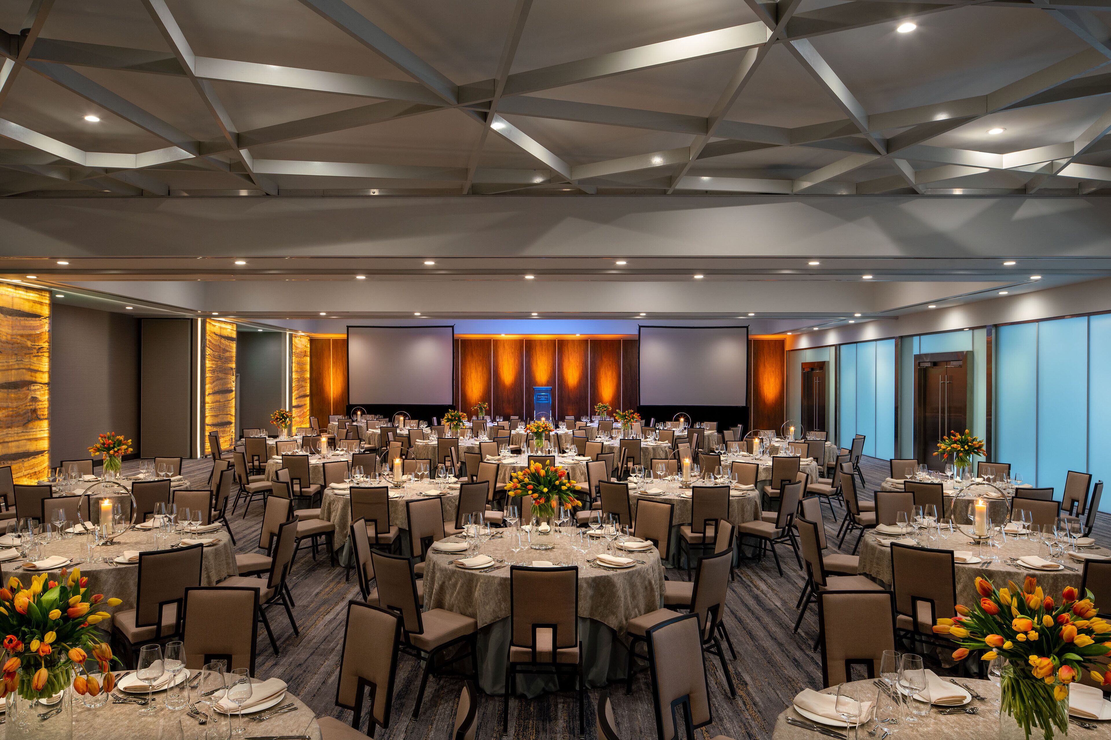 A large banquet hall with round tables set for dining, equipped with chairs and table settings.